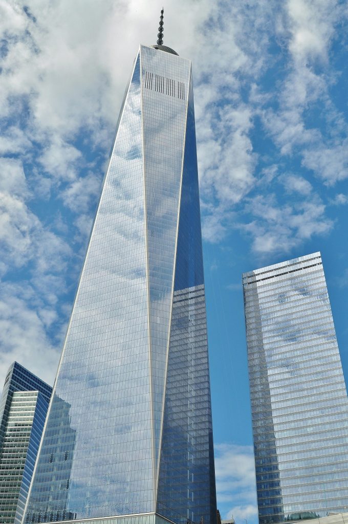 A striking view of One World Trade Center reflecting clouds in New York City.