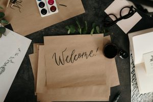 Welcome A creative workspace featuring calligraphy, envelopes, and art supplies for crafting personalized welcome cards.